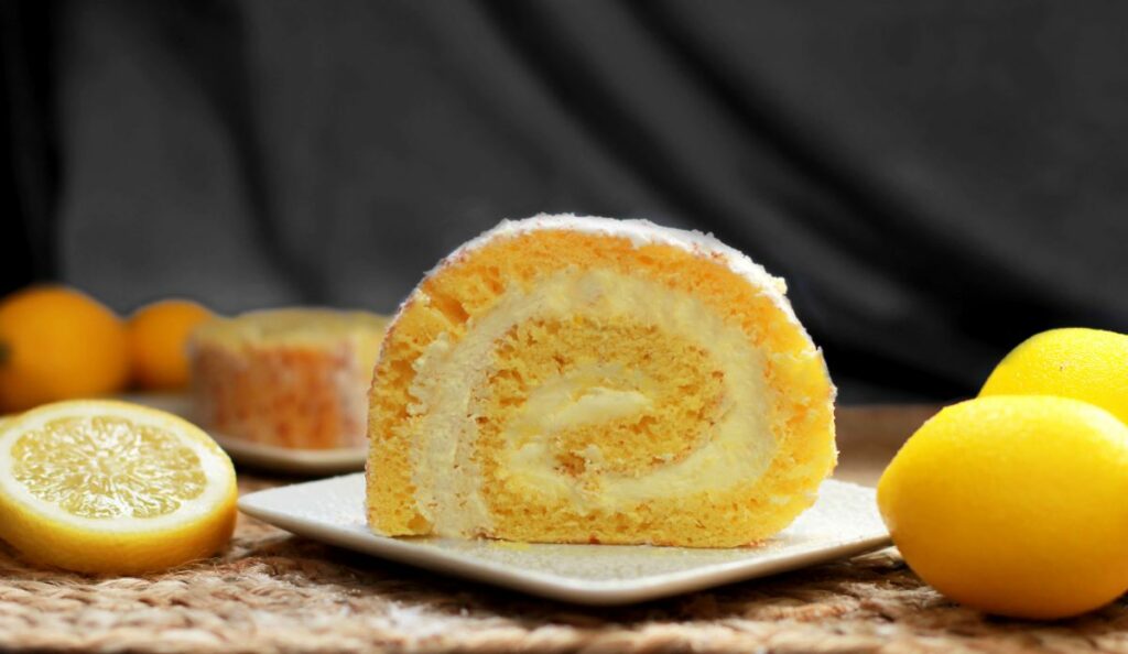 Picnic Desserts - Slice of Lemon Creme Cake Roll on plate with lemons