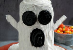 Ghost cake roll with bowl of candy corn in background