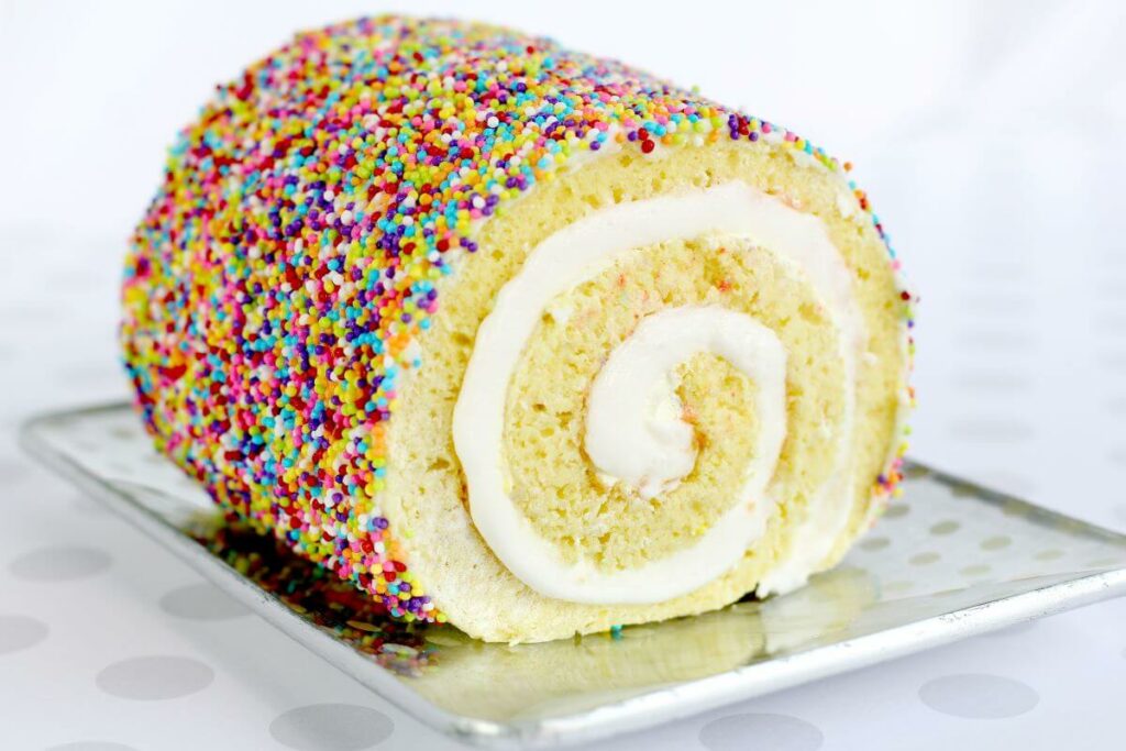 Sprinkle Cake Roll - lemon cake roll on metal serving tray, covered in sprinkles