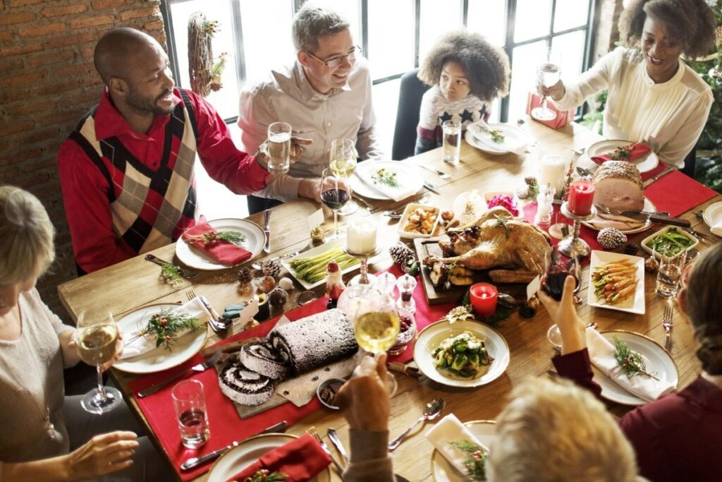 Essentials for Holiday Entertaining - Family and friends at holiday table with food and drinks