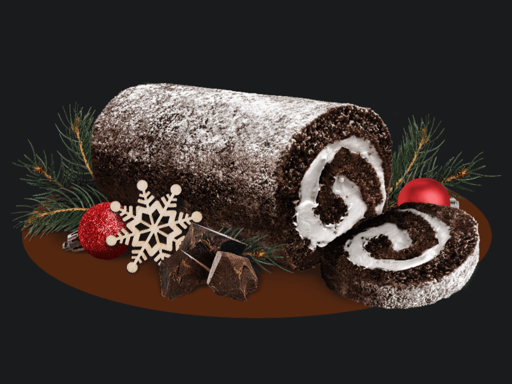 Chocolate Creme cake roll with slice surrounded by Christmas ornaments, snowflakes, and pine branches