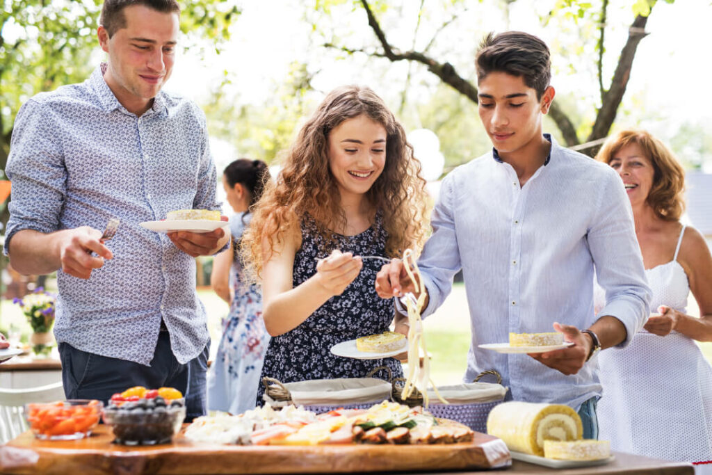 Tips for Garden Party Food - Three people outside at food table carrying plates of cake roll slices