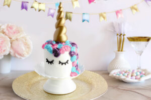 Unicorn Cake Roll on platter that's on a table with party decorations and bunting