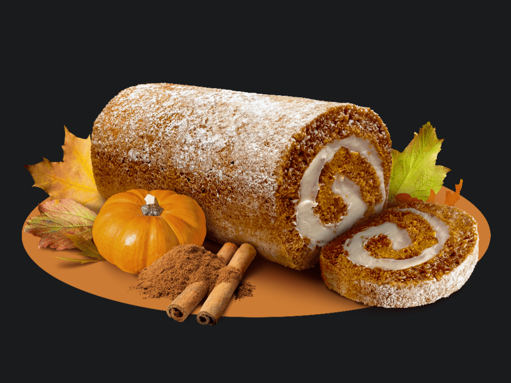 Dutch Apron Bakery Pumpkin Cake Roll surrounded by leaves, small pumpkin, and cinnamon sticks