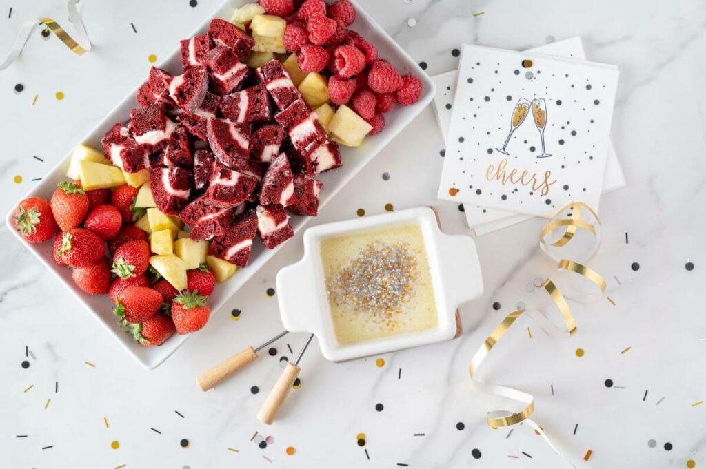 New Year's Eve Desserts - White Chocolate Champagne Fondue with plate of goodies for dipping, confetti, and napkins
