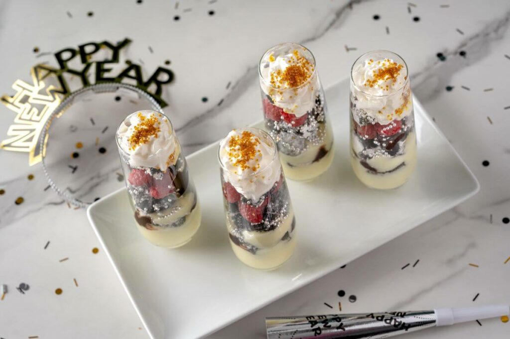 Sparkling Mini Parfaits surrounded by confetti, New Year's Eve hats, and noisemaker