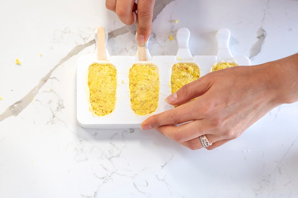 Adding popsicle sticks to the molds of the cakesicles