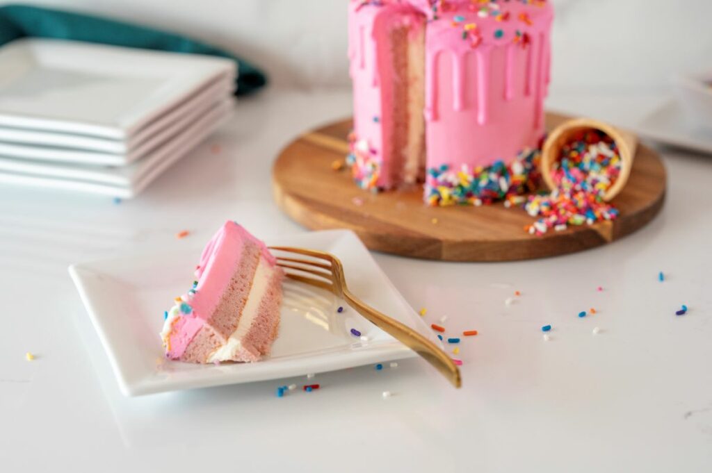 A slice of the Dripping Ice Cream Cone cake roll on a plate with the full cake roll in the back.