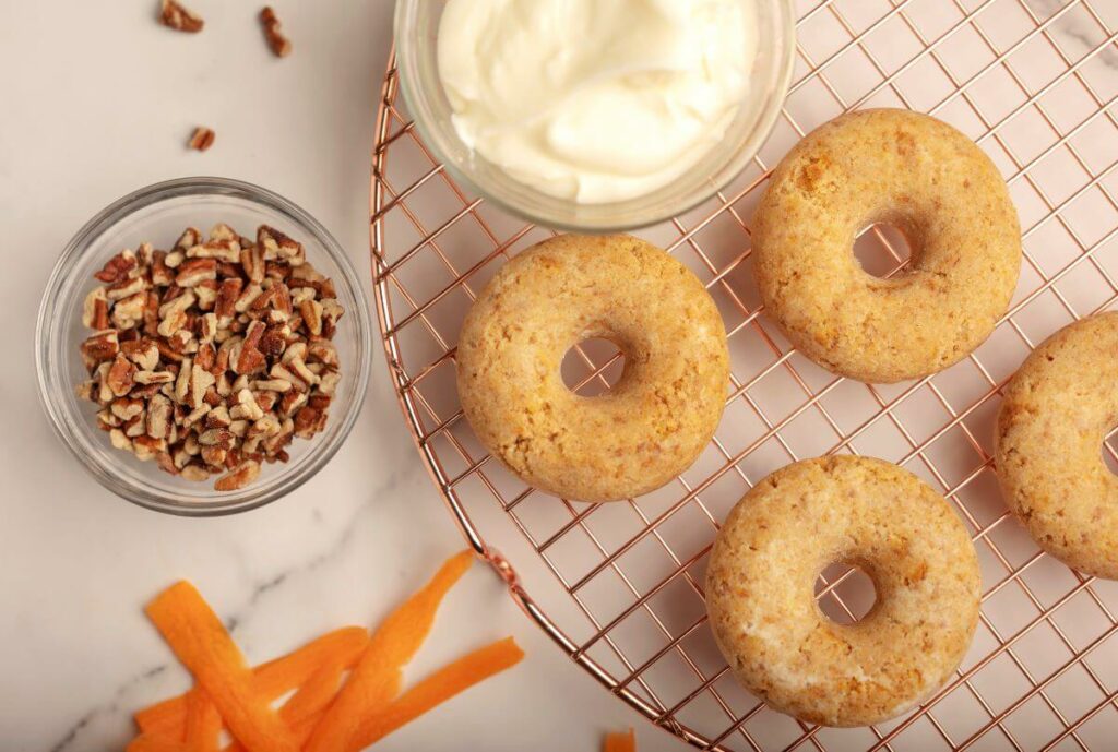 Image showing the ingredients you'll use to make your donuts: Carrot Cake Cake Roll mixed up and molded to look like donuts, cream cheese frosting, and nuts.
