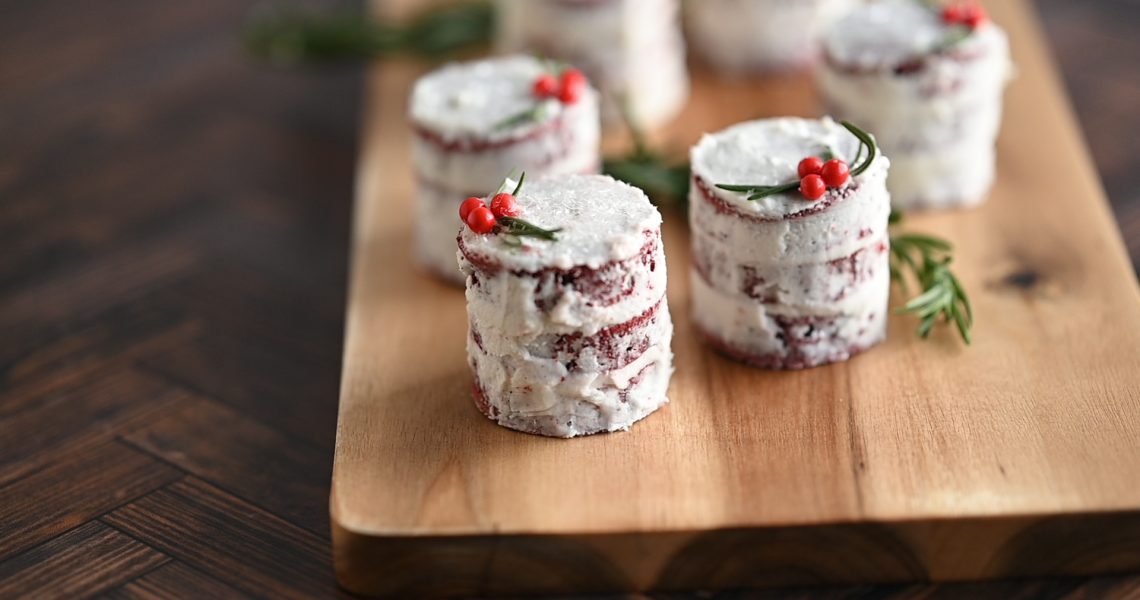 Christmas Petit Fours - stacked cakes covered in icing and sprinkles with rosemary sprigs and red pearl sprinkles.