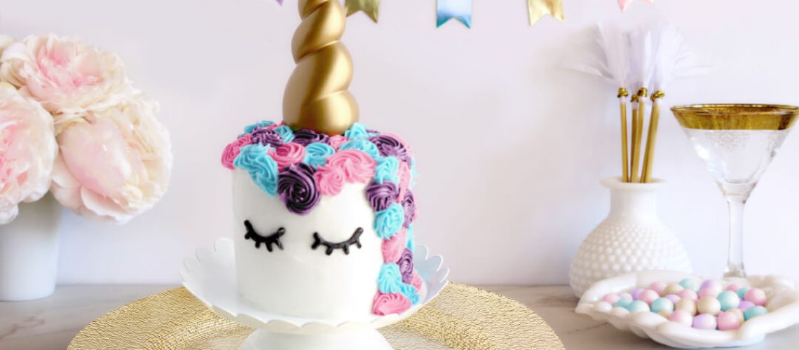 Unicorn Cake Roll on platter that's on a table with party decorations and bunting