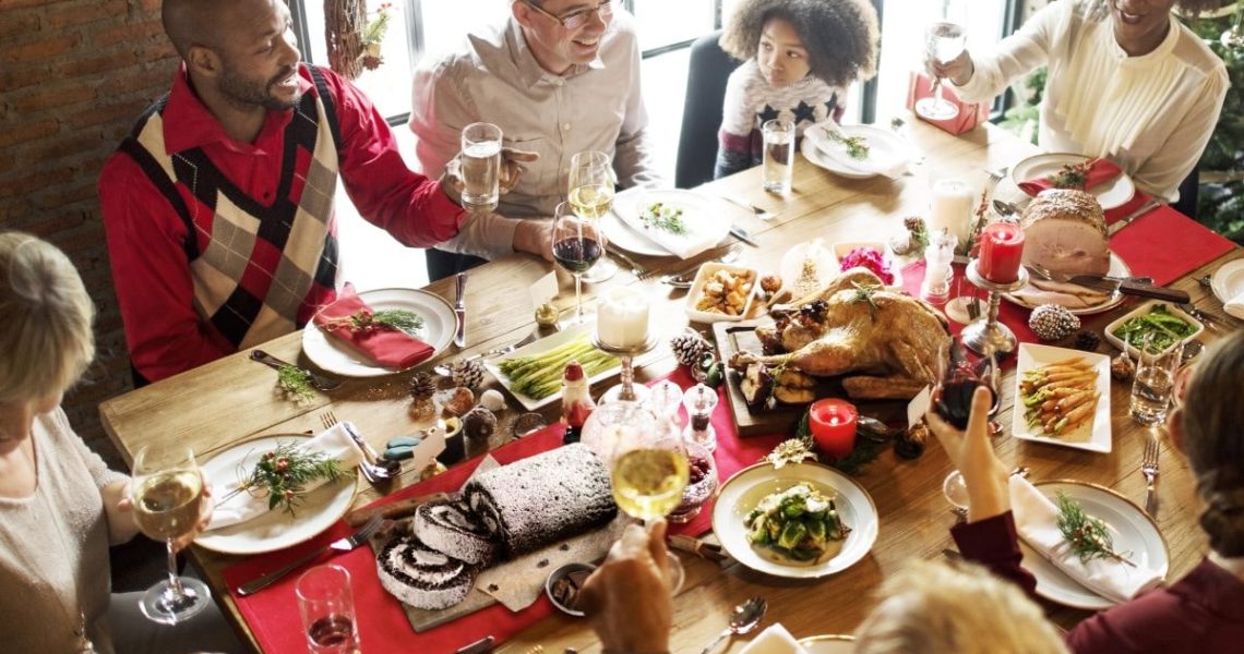 Essentials for Holiday Entertaining - Family and friends at holiday table with food and drinks